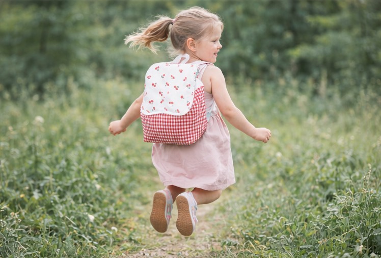 Mochila cerezas niña saltando